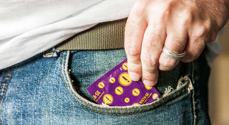 Homem tirando um pacote de preservativo do bolso
